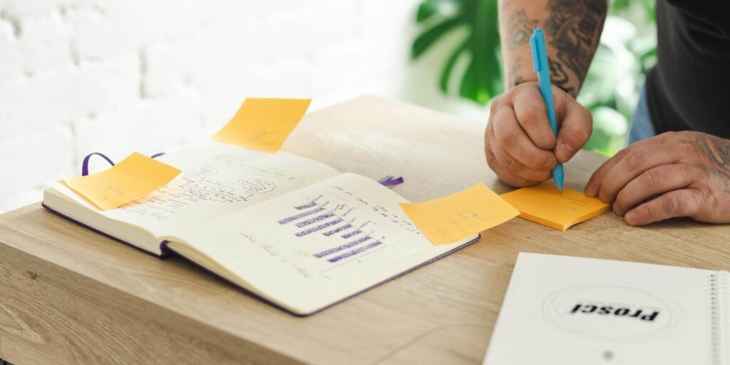 A man ideating notes with two notebooks in the foreground